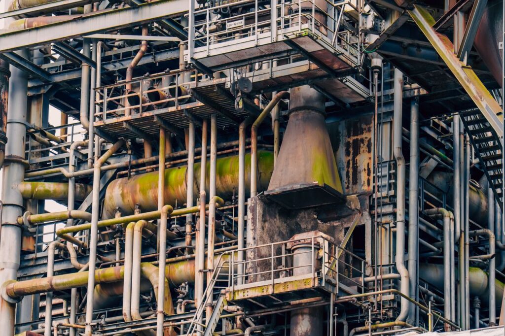 Close-up of an intricate network of rusted pipes and metal structures in an abandoned industrial plant.